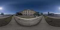 a 360 - fisheye photograph looking up at the sky and buildings behind them while some skateboarders are riding on pavement