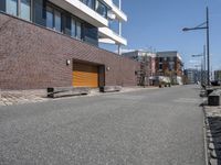 a bricked area with a parking lot on each side of it and some buildings in the back ground