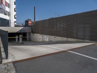 an empty parking lot in front of a tall building with doors to allow people to leave