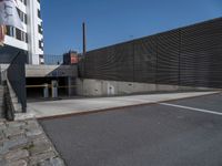 an empty parking lot in front of a tall building with doors to allow people to leave