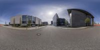 a street and some buildings with cars driving by on the side of it is in a fisheye lens