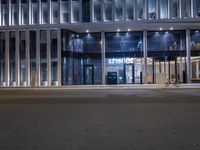 a car is parked in front of an office building at night time, with a bicycle chained to the post