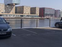 a couple of cars are parked near a bridge in the city with buildings behind it