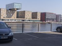 a couple of cars are parked near a bridge in the city with buildings behind it