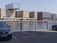 a couple of cars are parked near a bridge in the city with buildings behind it