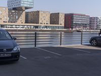 a couple of cars are parked near a bridge in the city with buildings behind it