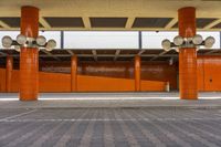 the orange building has two large pillars holding two speakers in each corner and there are brick pavers below them