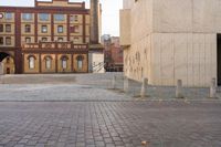 an empty bricked sidewalk in front of a tan building and fire hydrant on the side