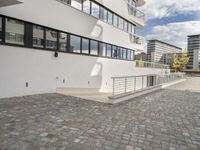 the brick walkway in front of a tall building on the opposite side with the stair