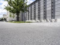 street view of a building with some trees near by it in an urban area next to buildings with lots of glass and stone