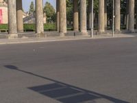 a person that is riding a skateboard near a pole and some columns with a sky background