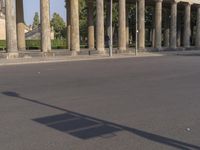 a person that is riding a skateboard near a pole and some columns with a sky background