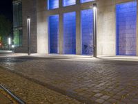 the people are sitting on bikes in front of blue windows and stone bricks are illuminated