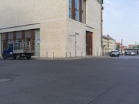 a street with cars parked in front of a tan building, on the corner and on the side