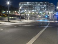 large building on the street with lights in front and other buildings nearby at night with no one moving