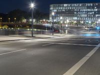 large building on the street with lights in front and other buildings nearby at night with no one moving