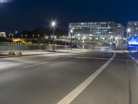 large building on the street with lights in front and other buildings nearby at night with no one moving