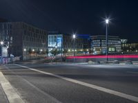 large building on the street with lights in front and other buildings nearby at night with no one moving