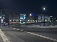 large building on the street with lights in front and other buildings nearby at night with no one moving