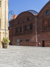 a man is using a cellphone in an open courtyard area in a building with red brick walls