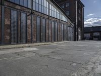 an old industrial building with large windows and glass panels on the front of it and empty street