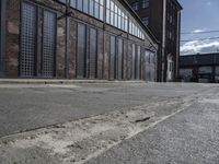 an old industrial building with large windows and glass panels on the front of it and empty street