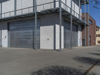 this is a building with several garage doors closed up at the front of it and people walking on the pavement