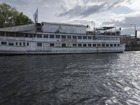 large body of water next to a building near the river with people on it and boats in the water