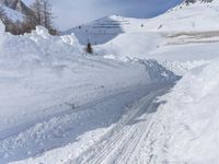 there are many piles of snow that have been piled up on this hill side on a ski slope