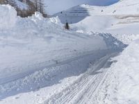 there are many piles of snow that have been piled up on this hill side on a ski slope