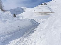 there are many piles of snow that have been piled up on this hill side on a ski slope