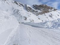 there are many piles of snow that have been piled up on this hill side on a ski slope
