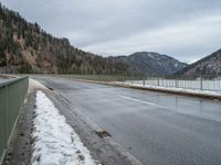 the asphalt is empty and the fence is completely empty of people and there are no people standing in the snow on the road