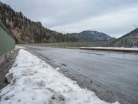 the asphalt is empty and the fence is completely empty of people and there are no people standing in the snow on the road