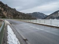 the asphalt is empty and the fence is completely empty of people and there are no people standing in the snow on the road