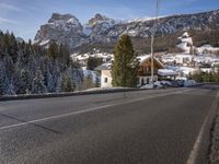 a road leads down to the side of a hill in front of a snowy mountain