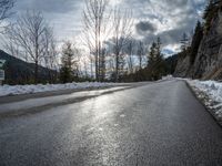 there is snow all over the asphalt of the mountain road in this picture you can see the road sign on the street below