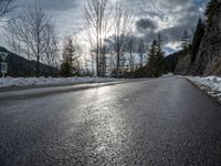 there is snow all over the asphalt of the mountain road in this picture you can see the road sign on the street below