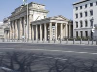 an empty city street and large columns in the background with some buildings lining the street