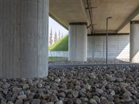 there is a pile of rocks underneath the bridge with a sky background the water near the structure has a long line of lines