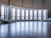 the empty space has a curved floor and a tall clock tower with an arched roof