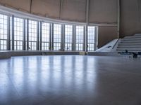 the empty space has a curved floor and a tall clock tower with an arched roof