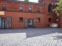 the entrance to the brick building is located near some windows and doors with windows open