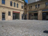 the sidewalk is paved with stones and has a bench in front of it, with no people inside