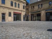 the sidewalk is paved with stones and has a bench in front of it, with no people inside