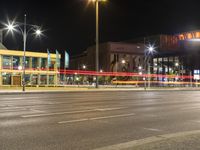 a large building on a street in an empty parking lot at night time with cars passing by