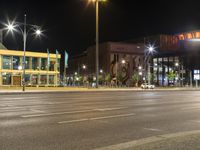 a large building on a street in an empty parking lot at night time with cars passing by