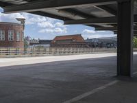 the view from under an overpass looking at the street below it, a clock tower in the distance and other buildings