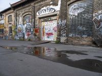 the water is almost completely visible in front of a graffiti covered building with windows on either side