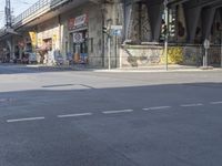 an old man in yellow shirt sitting on bike on side of road with graffiti underpass